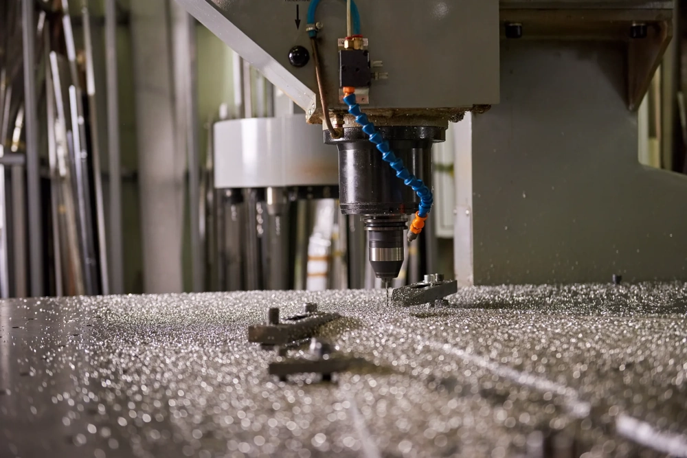 Precyzyjna obróbka CNC metalowej płyty z widocznymi wiórami i elementem mocującym